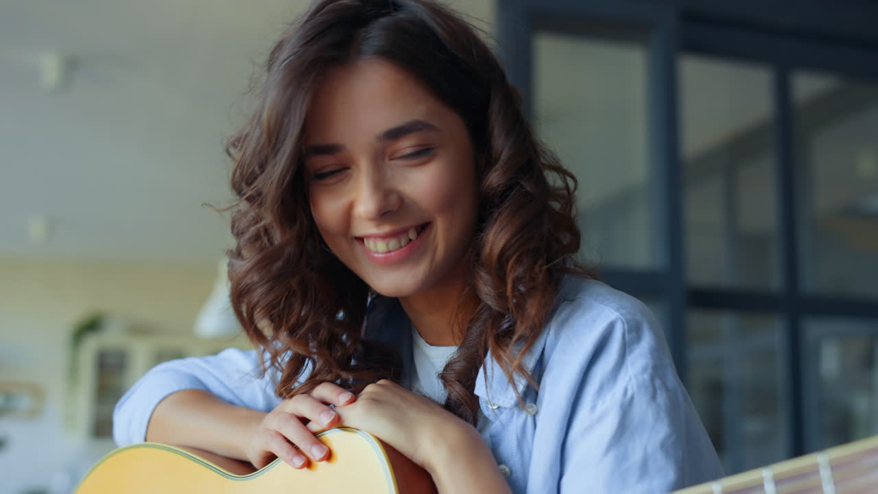 mujer con guitarra riendo a la cámara en casa. chica con guitarra acústica