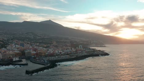 aerial panorama of puerto de la cruz resorts and pools surrounded by sea waves on sunset, tenerife, canary islands, spain.