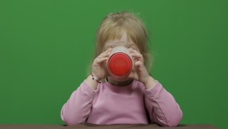 girl sitting at the table and drinks yogurt milk. funny milk mustache