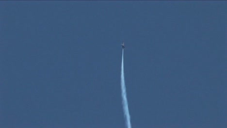 a blue angels jet barrel rolls straight into the sky