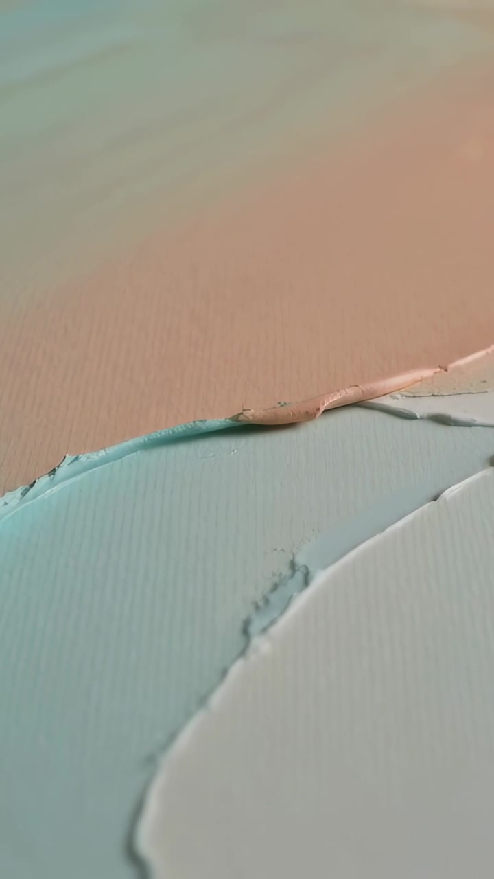 Vertical video: Panning camera revealing layered teal and peach paint on table showing texture