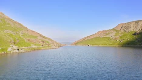 low-level aerial view over lake llyn llydaw in snowdonia national park on a bright and sunny day with weather favourable for outdoor pursuits and hiking