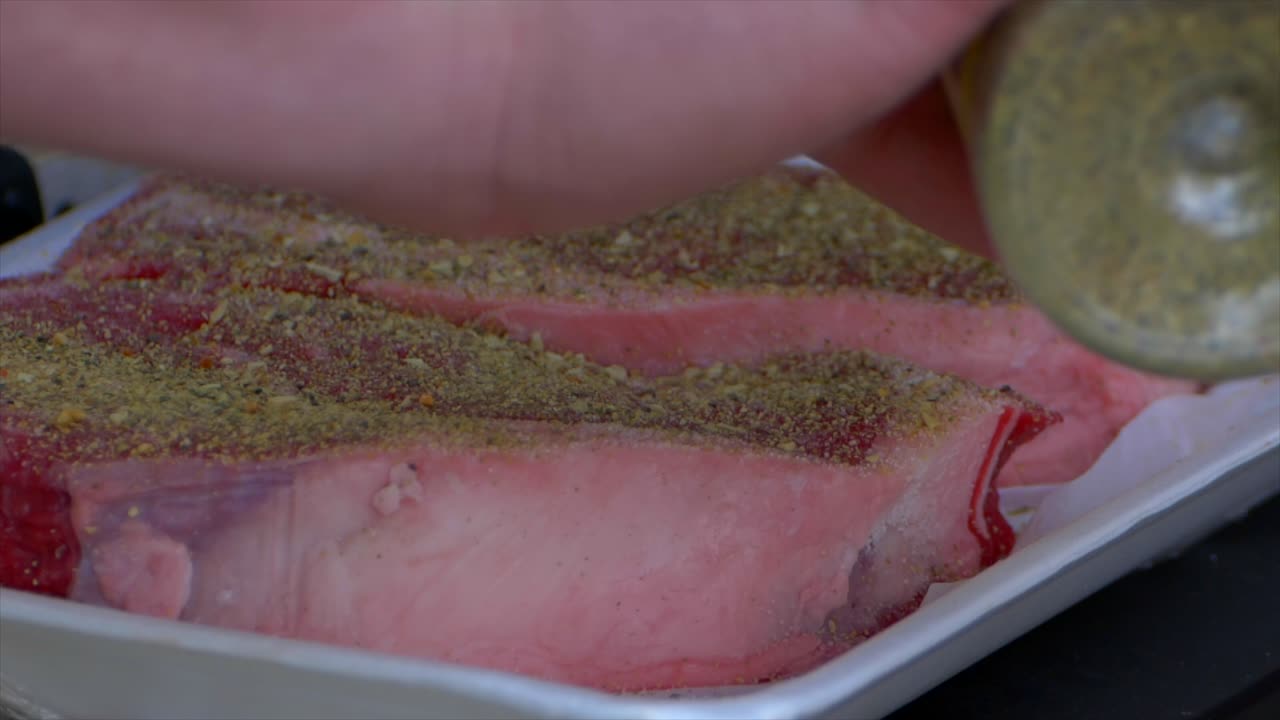 생 립아이 스테이크 전체에 향신료를 붓는 손