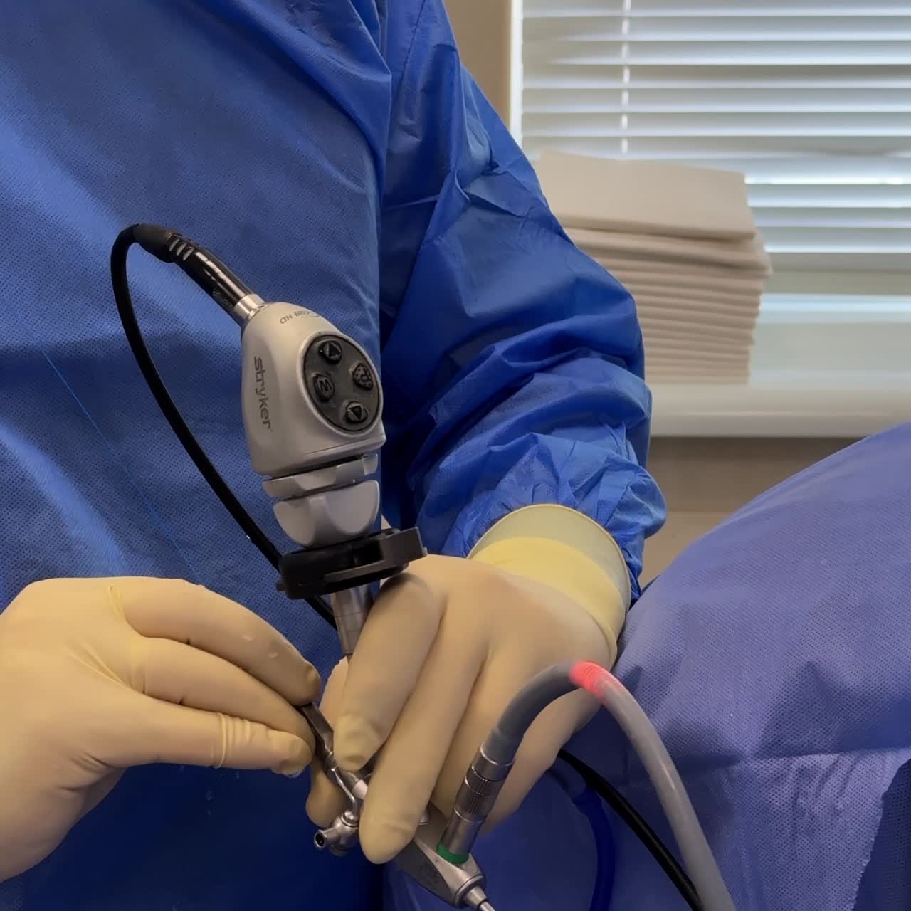 Gloved hands of a male surgeon hold endoscopic tool device. Close up. Vertical screen