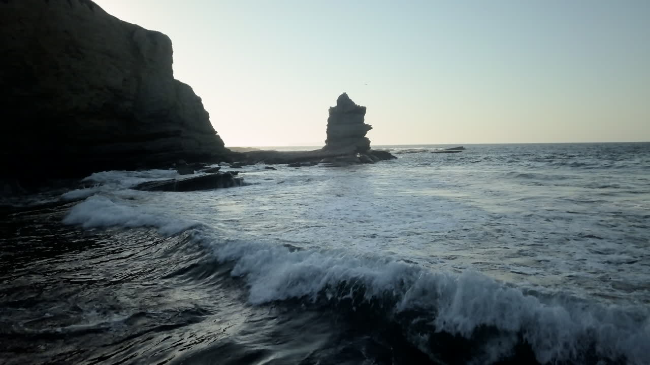 antena - sobrevuelo del océano cerca del agua con el sol como contraluz