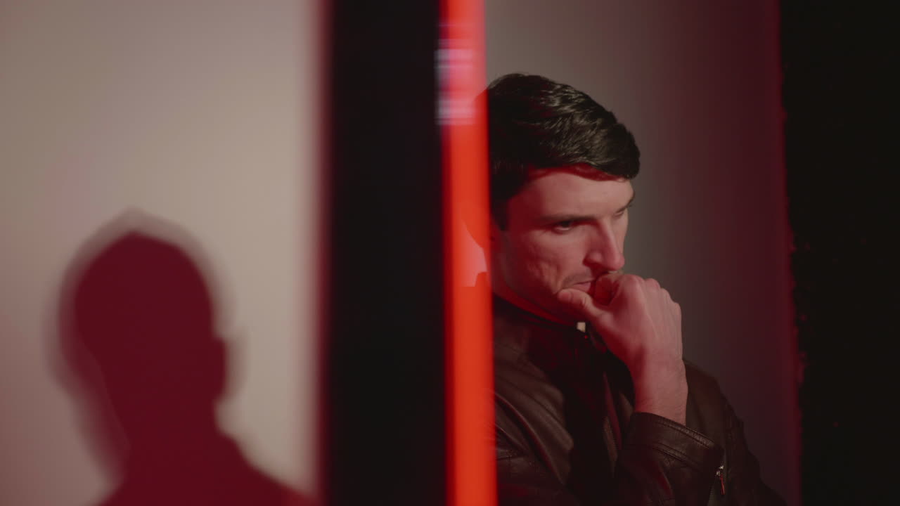 un hombre guapo con la mano en la barbilla mientras está de pie contra un fondo blanco en el estudio - plano medio