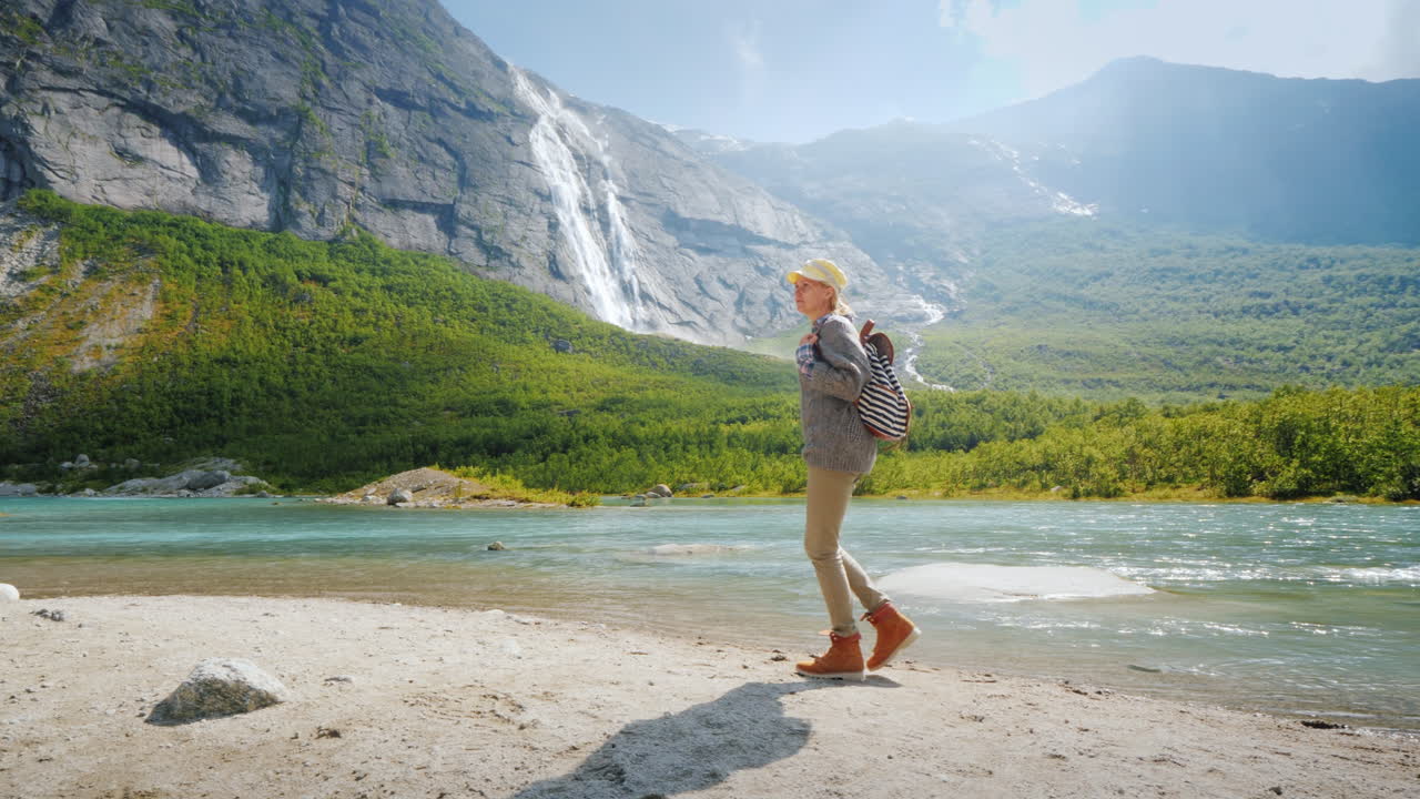 una mujer turista camina sola rodeada de naturaleza majestuosa - montañas con cascadas en la cima del tra