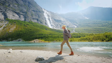 una mujer turista camina sola rodeada de naturaleza majestuosa - montañas con cascadas en la cima del tra