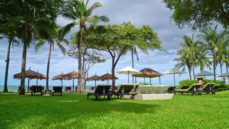 umbrella and beach chair with coconut palm tree and sea beach background and blue sky - holiday and vacation