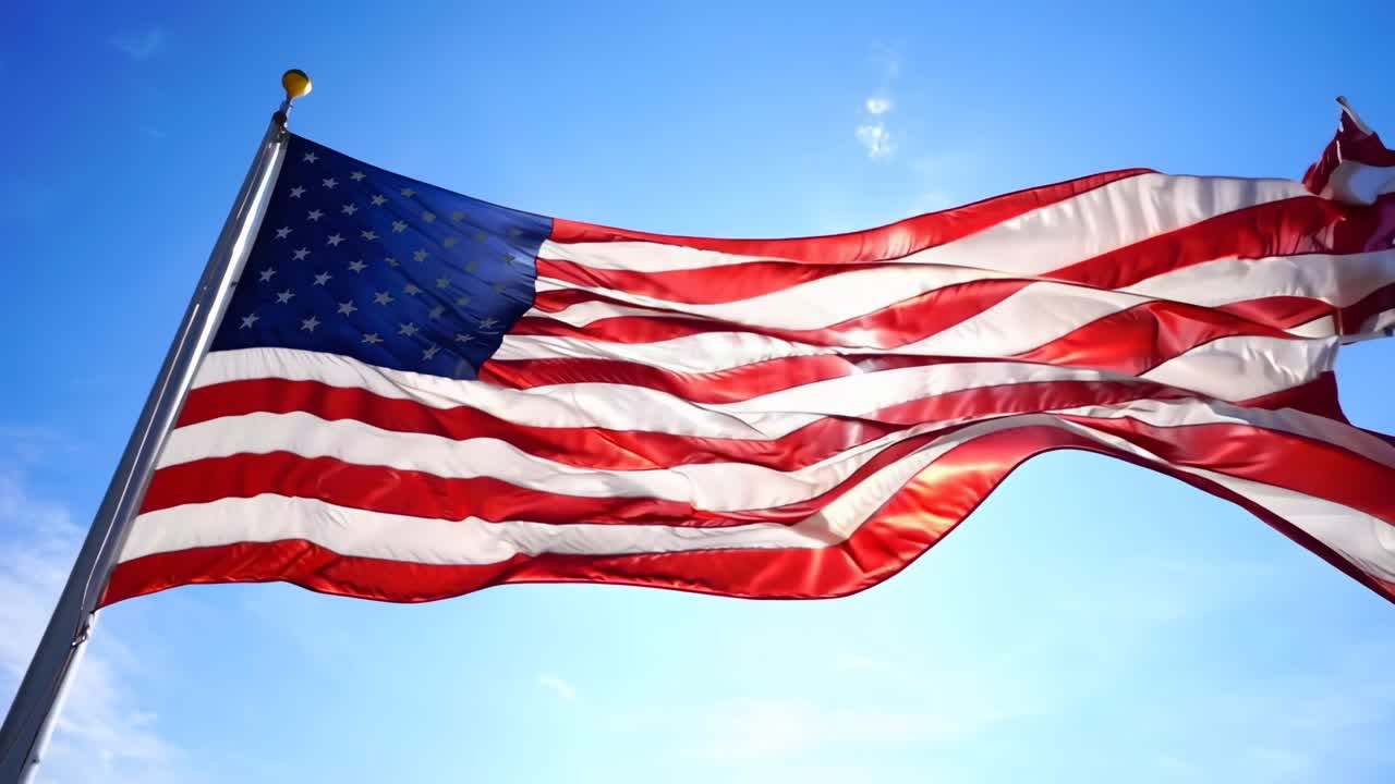 Video i lav engel af det amerikanske flag, der blafrer mod en klar, blå himmel og symboliserer patriotisme