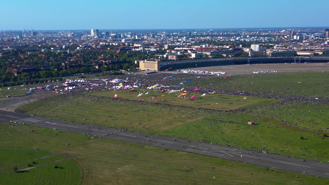 Large crowd of people gathering at the Tempelhofer Feld giant kite festival in Berlin, Germany. Great aerial view flight descending drone