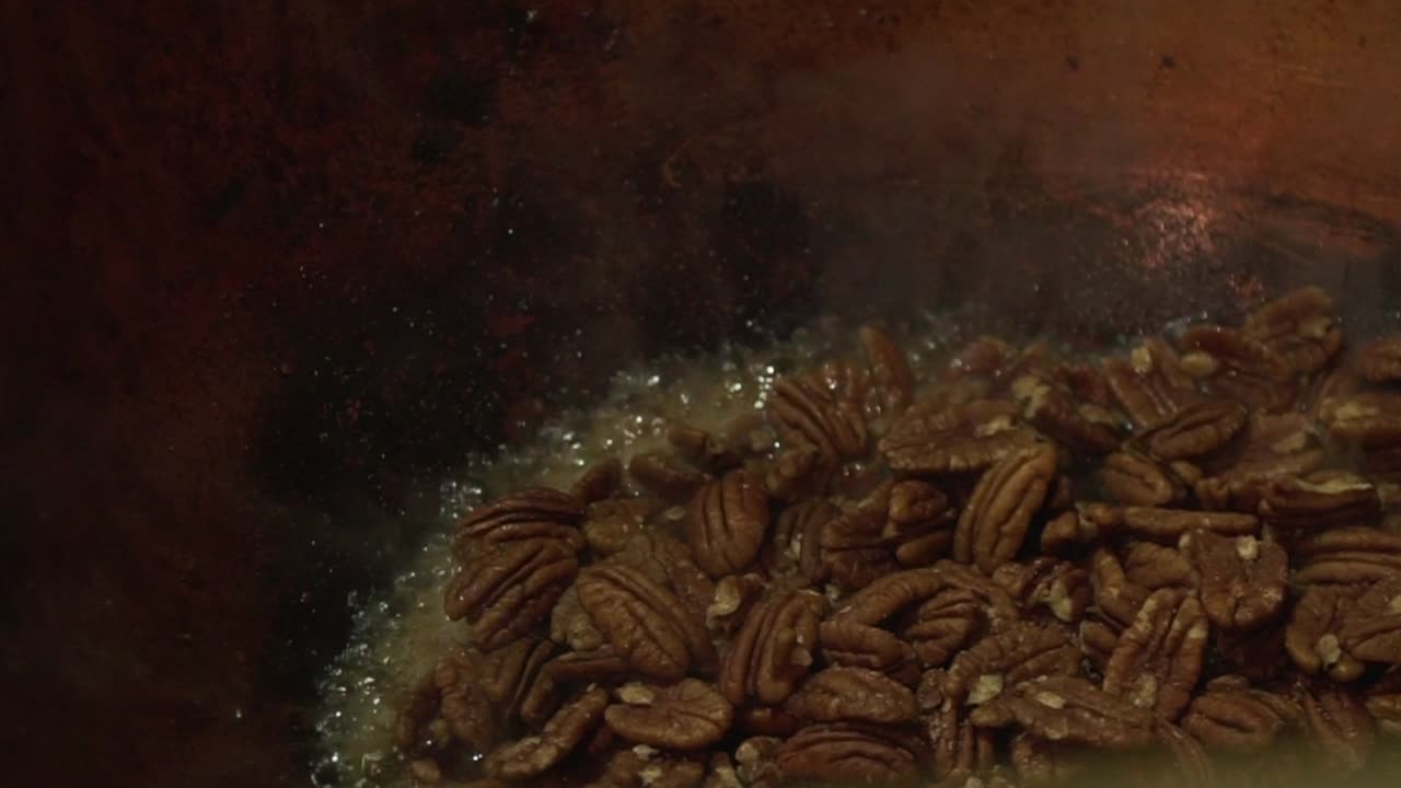 Close up slow motion shot of pecan nuts being roasted and caramelised