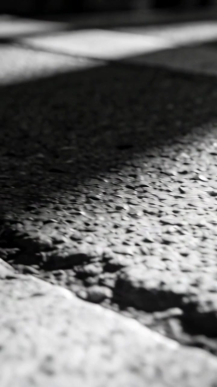 Vertical video: Sliding low camera, dolly starting at curb, revealing asphalt, diagonal light bands