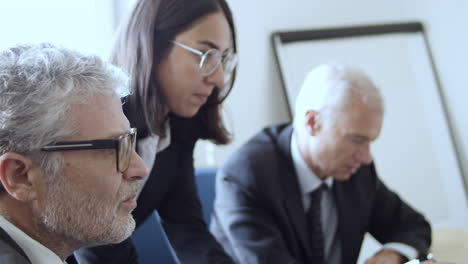 reunión profesional femenina seria con dos hombres de negocios analizando datos