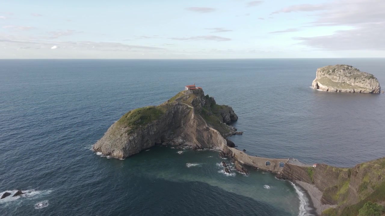 Ripresa aerea con drone che rivela il paesaggio dell'isolotto di Gaztelugatxe, location della battaglia di Game of Thrones alla luce del giorno