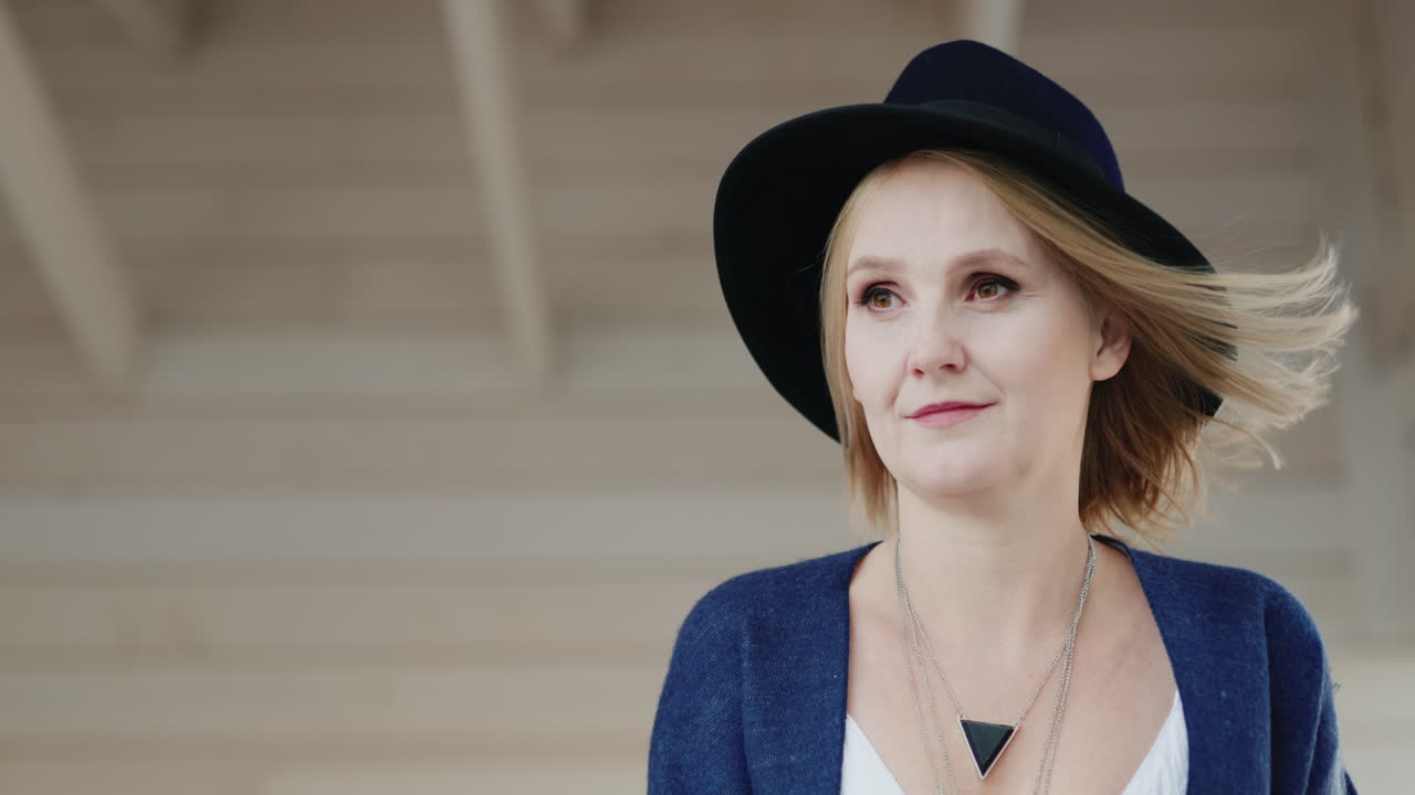 집 테라스에 있는 모자를 쓴 세련된 중년 여성의 초상화