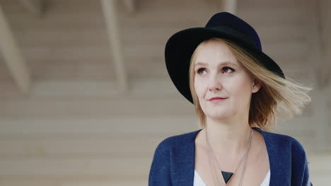 portrait of a stylish middle-aged woman in a hat on the terrace of her house