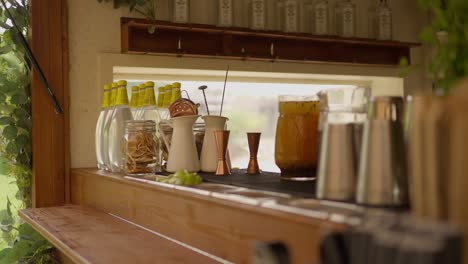 rustic outdoor bar setup with bottles, jars, and cocktail tools, ready for a casual gathering