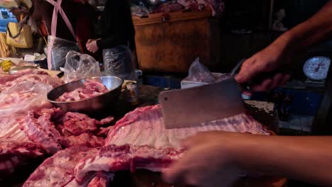 butcher cuts pork ribs in a busy market stall