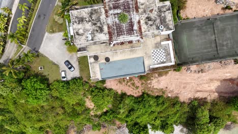 drone footage captures an empty tennis court and surrounding greenery in phuket, thailand, highlighting a serene, abandoned atmosphere