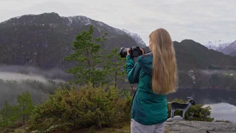 mujer joven fotografiando el accidentado paisaje noruego con una nueva cámara sin espejo