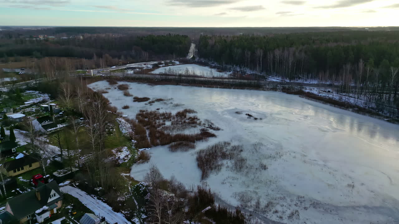 Panoraamalento jäätyneen järven, esikaupunkimaiseman, esikaupunkikaupungin ja moottoritien yllä