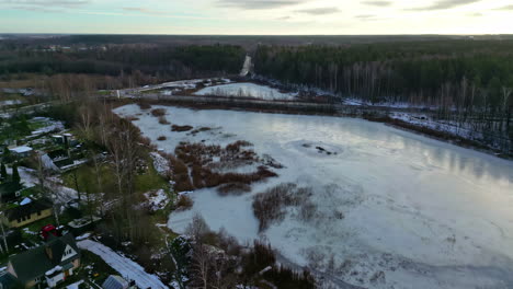 Panoramic-aerial-fly-above-frozen-lake-suburban-landscape-suburban-city-highway