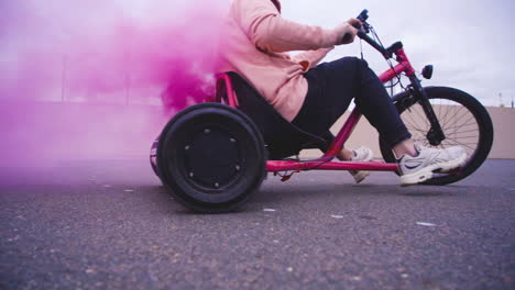 un emocionante paseo dinámico en triciclo con un hermoso efecto de humo rosado en un entorno urbano vibrante