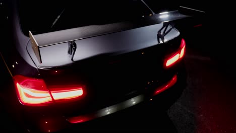 detail shot of the back rear light with spoiler of a sports car at night