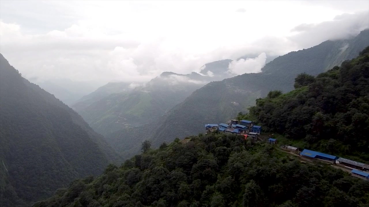 Veduta aerea di un pittoresco villaggio di montagna annidato tra cime aspre. Mostra case affascinanti e tradizionali e paesaggi sereni e incontaminati, evidenziando il tranquillo isolamento del villaggio.