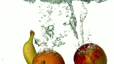 Manzana-Plátano-Y-Naranja-Sumergiéndose-En-El-Agua-Sobre-Fondo-Blanco.