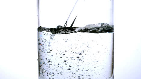 water being poured into a glass over white background