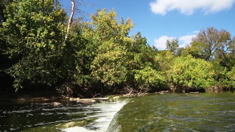 Wasser-Fließt-über-Ein-Großes-Felsbett,-Wasserfall-In-Der-Bildmitte,-Wasser-Tropft-über-Den-Wasserfall-Und-Fließt-Weiter-Und-Schäumt-Aus-Dem-Tropfen