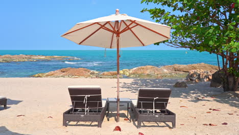 two deckchairs under parasol in tropical beach rocky beach on a sunny day