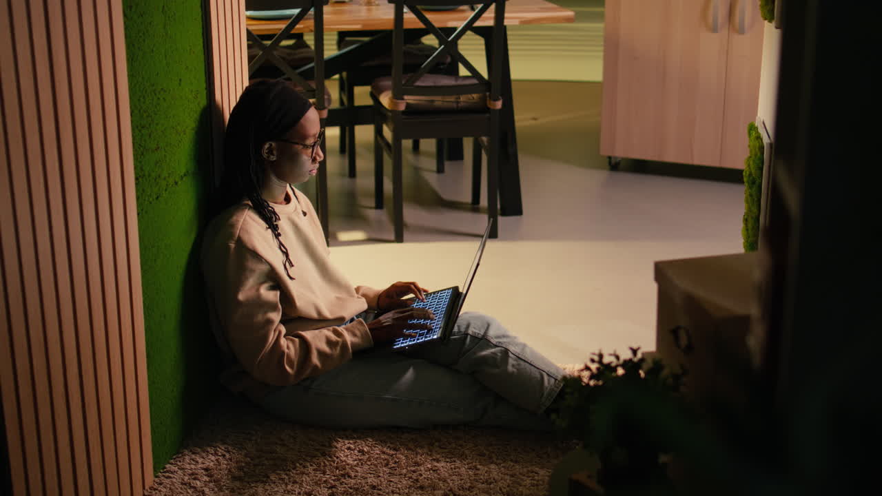 Young black woman with laptop sitting in the hallway in cozy warm interior