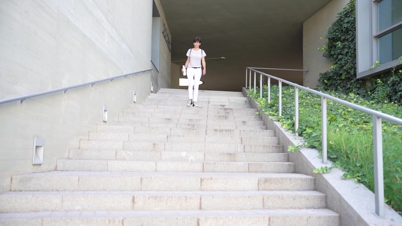 A person is walking down a set of outdoor steps situated in a modern architectural setting