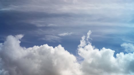 White-puffy-clouds-roll-across-bottom-of-screen,-blue-sky-skyscape-time-lapse