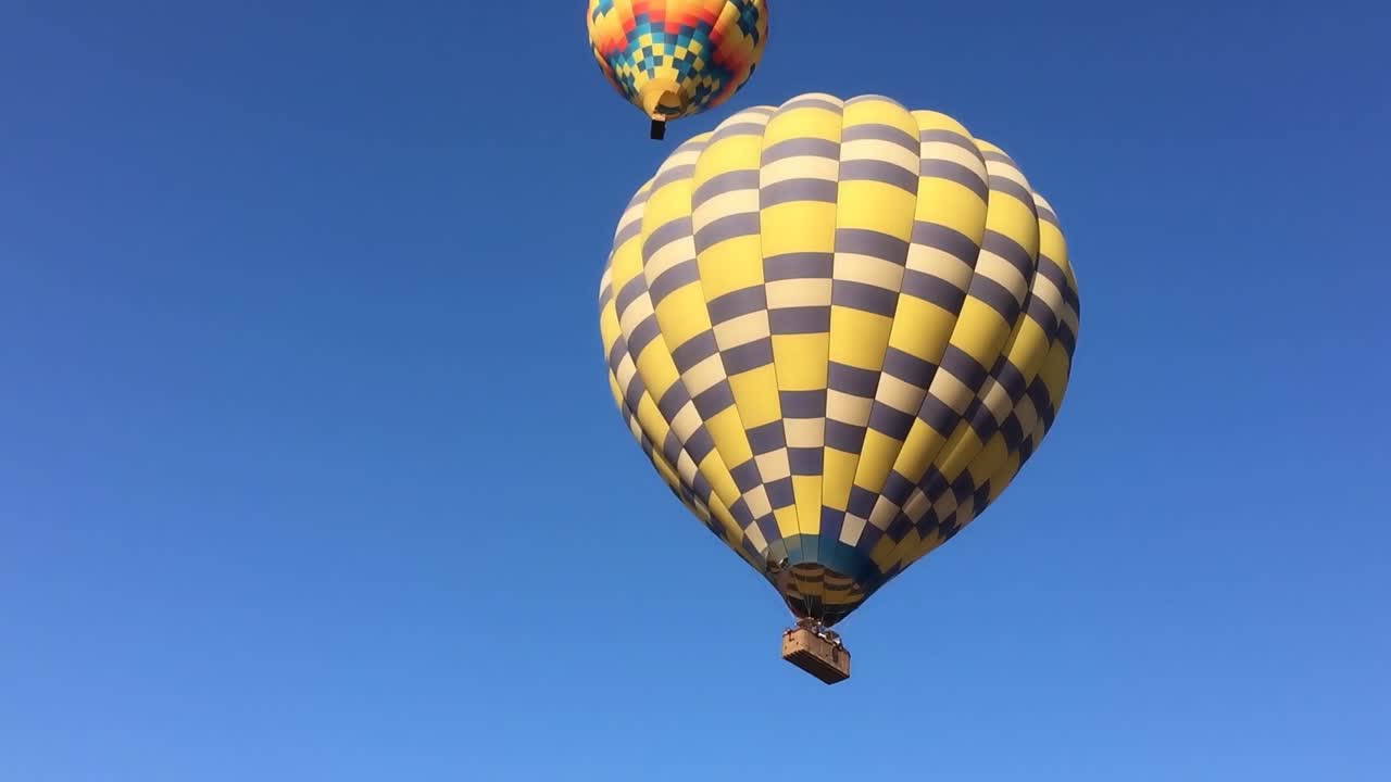 ms en globos de aire caliente mientras descienden con el cielo azul en el fondo