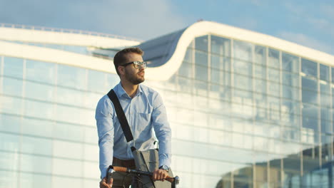 Handsome-man-in-business-style-riding-a-bicycle-and-stopping-in-front-of-the-camera