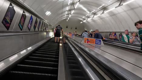 pasajeros que usan escaleras mecánicas en la estación de metro de londres