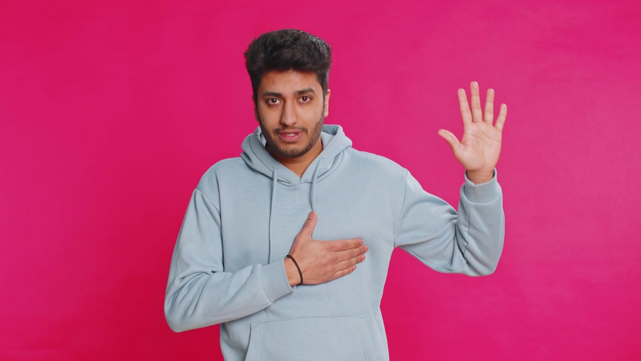 Indian man raising hand to take oath promising to be honest and to tell truth keeping hand on chest