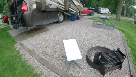 pan-of-campsite-with-satellite-antenna-near-a-camp-fire-ring-and-RV-coach