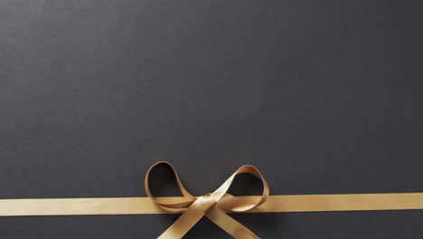 video of gold gift ribbon and bow with copy space on black background