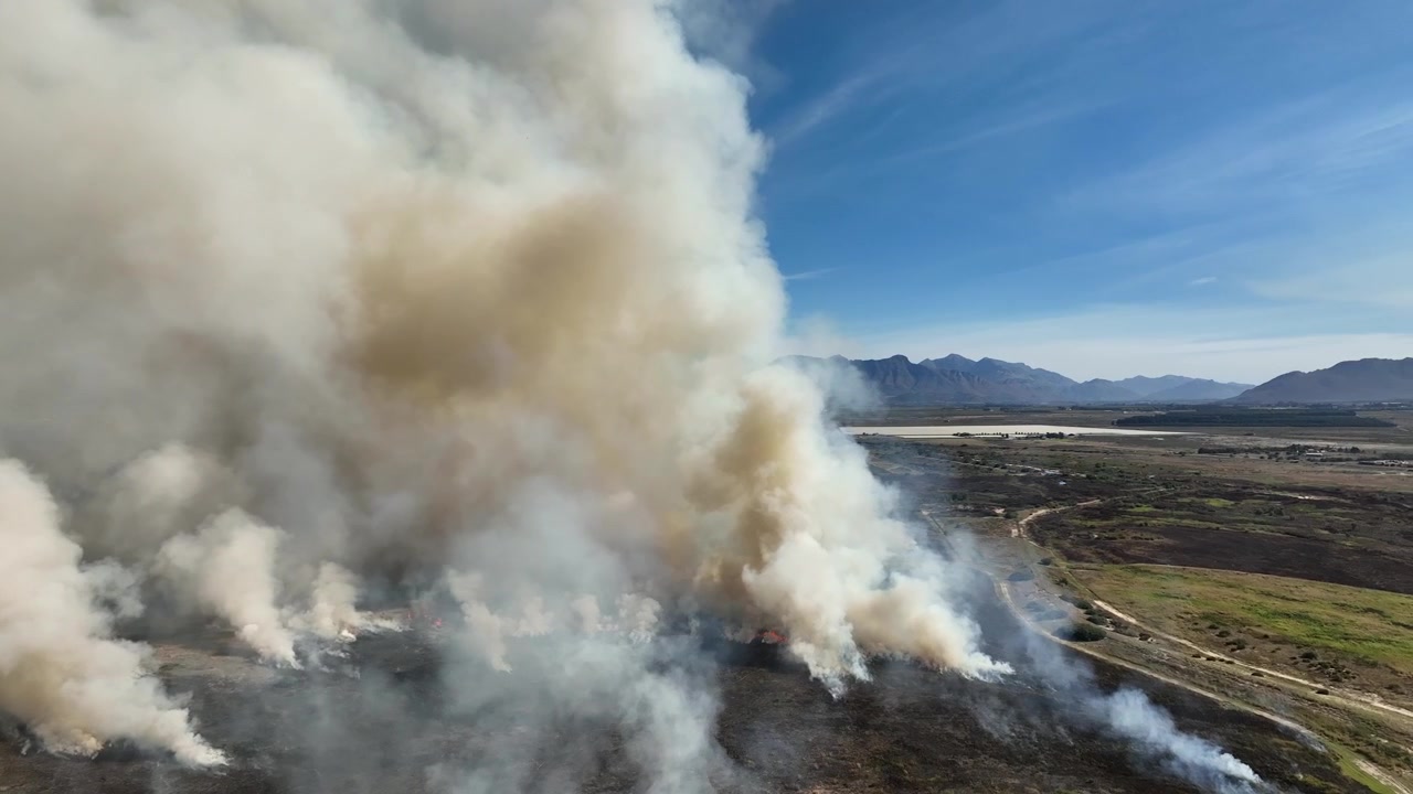 Veduta aerea di un incendio attivo di sterpaglie che produce un fumo denso e imponente