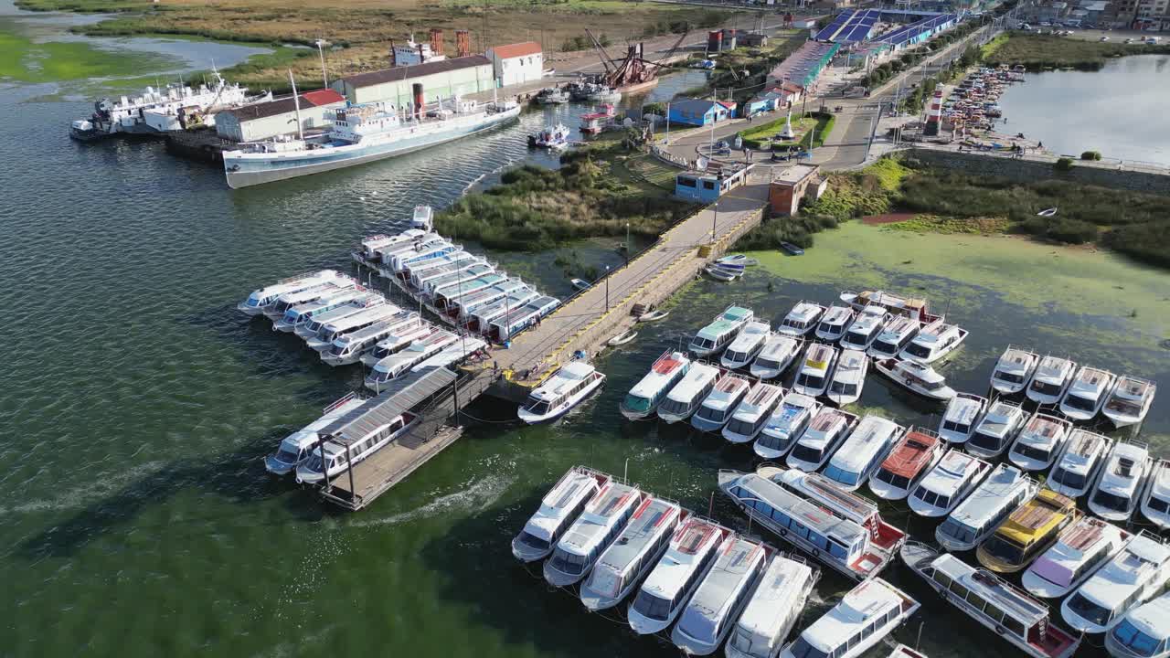Aerial orbits tour boats lined up at pier on Lake Titicaca, Puno Peru