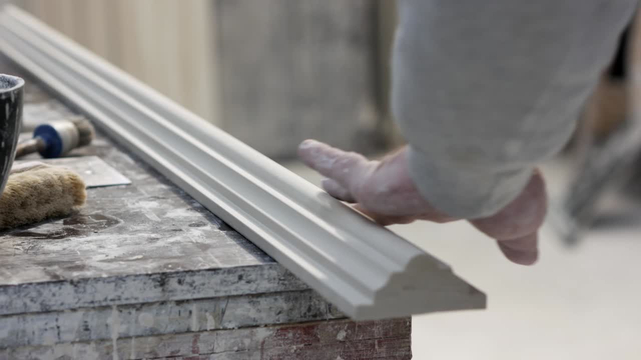 Man’s hand touching gypsum profile in mounding workshop, closeup
