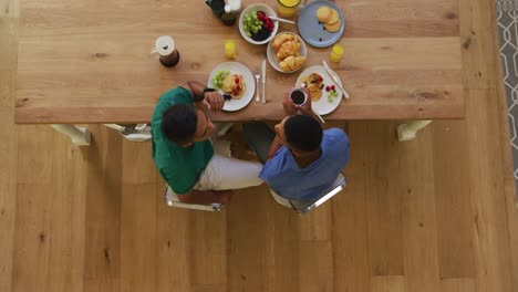 overhead view of mixed race gay male couple having breakfast at table