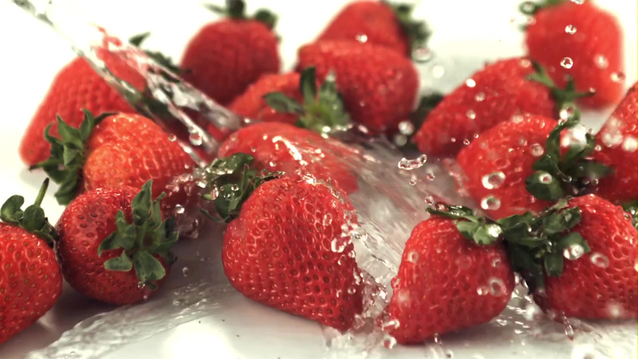 Acqua che schizza su fragole rosse fresche su sfondo bianco.