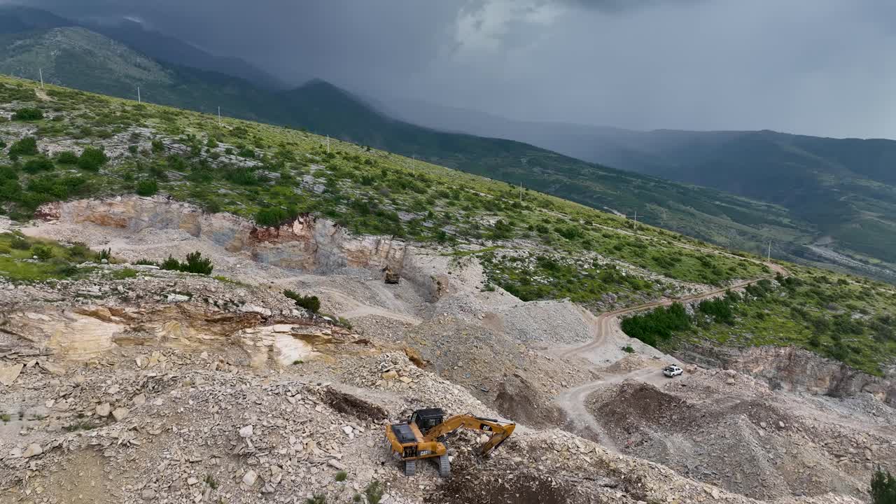 Excavator digging and clearing rocks on the side of the mountain