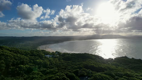 byron bay, nsw australia, with lush green hills and a shimmering coastline, aerial view